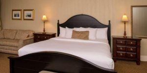 king bed with white bedding and dark wood bedframe in riverview suite