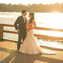 bride and groom staring lovingly at one another with water background